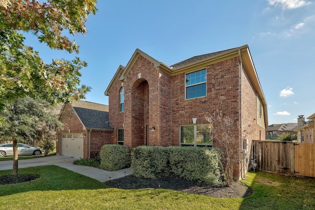 traditional-style house with a garage, brick siding, a front lawn, and fence