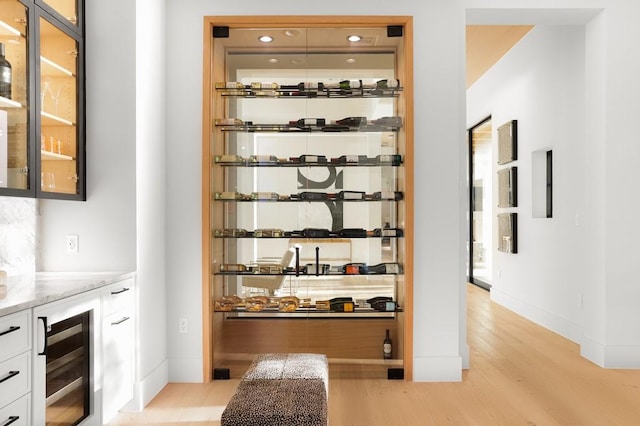 wine area with beverage cooler and light hardwood / wood-style floors