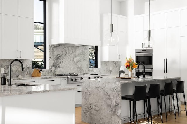 kitchen with white cabinetry, sink, and light stone counters