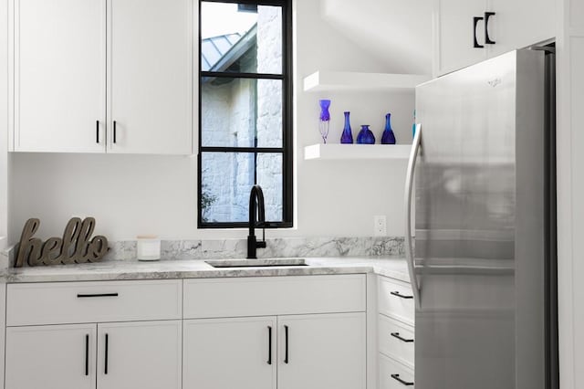 kitchen with white cabinets, sink, and stainless steel fridge