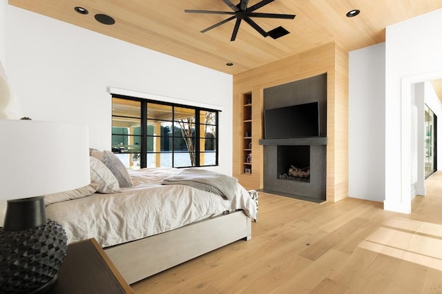 bedroom with a fireplace, light hardwood / wood-style flooring, and wooden ceiling