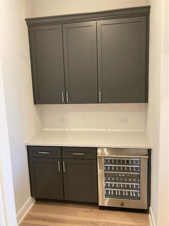 bar featuring light stone countertops, a mail area, beverage cooler, and light hardwood / wood-style floors