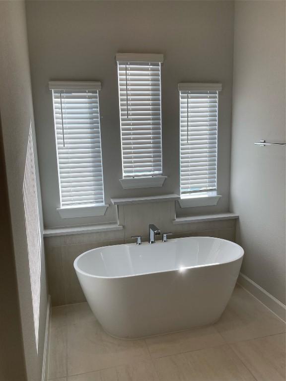 bathroom featuring a wealth of natural light, tile patterned floors, and a bathtub