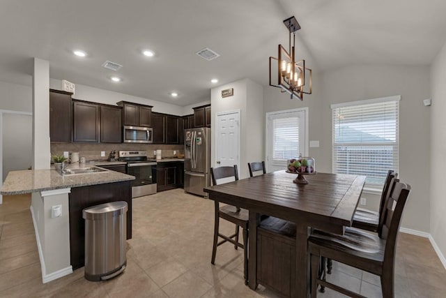 interior space with stainless steel appliances, a peninsula, visible vents, and dark brown cabinetry