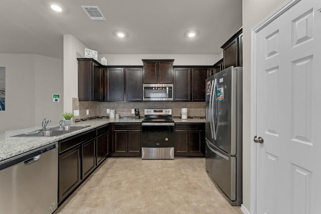 kitchen featuring visible vents, decorative backsplash, appliances with stainless steel finishes, dark brown cabinets, and a sink