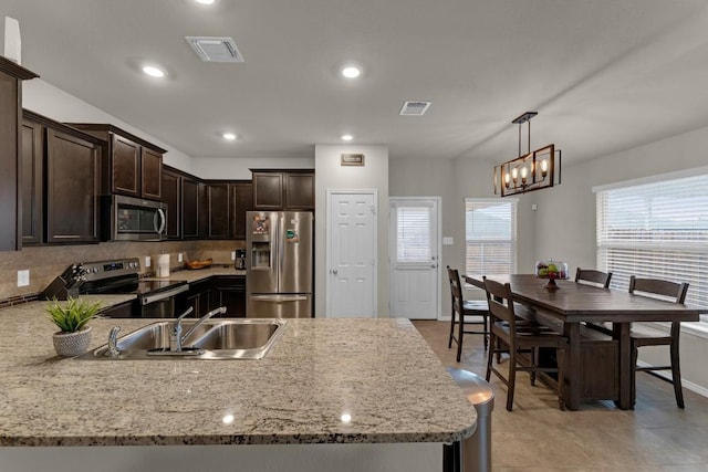 kitchen featuring dark brown cabinetry, tasteful backsplash, visible vents, stainless steel appliances, and a sink