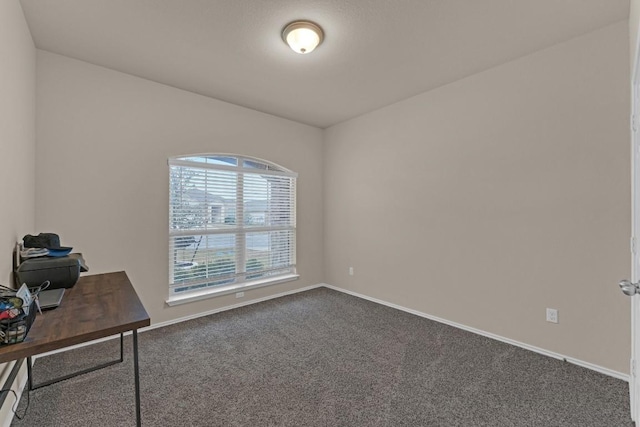 unfurnished office with dark carpet and baseboards