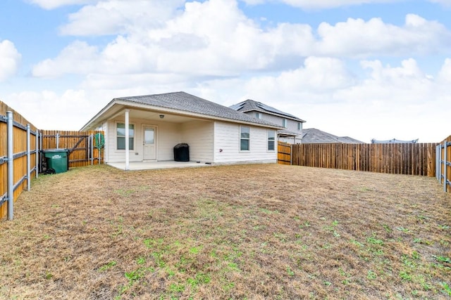 back of property with a yard, a patio area, and a fenced backyard