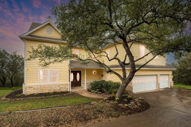 traditional home featuring a garage, stone siding, and driveway