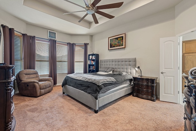 bedroom with ceiling fan, a tray ceiling, and carpet