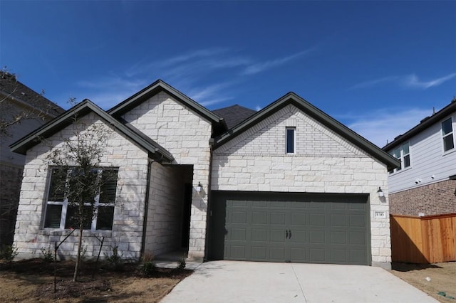 view of front of property featuring a garage, stone siding, fence, and driveway