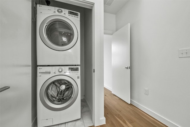 washroom with stacked washer and dryer and light hardwood / wood-style floors