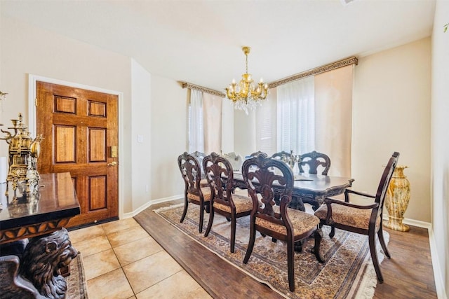 dining space with light tile patterned flooring, a notable chandelier, and baseboards