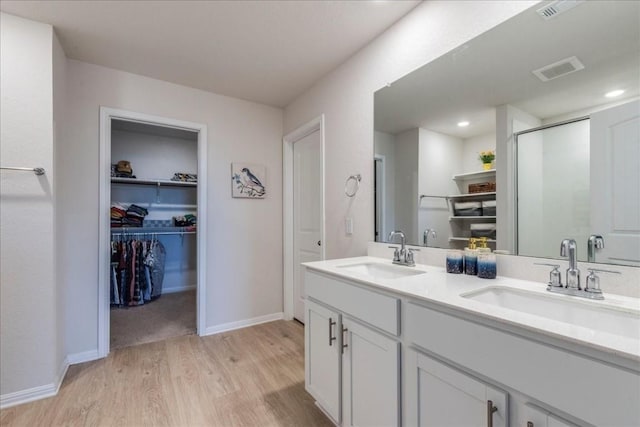 2501 Bear Juice Vw, Leander, TX 78641 - full bathroom featuring wood finished floors, double vanity, a spacious closet, a stall shower, and baseboards
