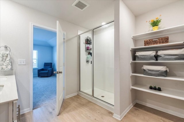 2501 Bear Juice Vw, Leander, TX 78641 - bathroom featuring wood finished floors, double vanity, a shower stall, and baseboards