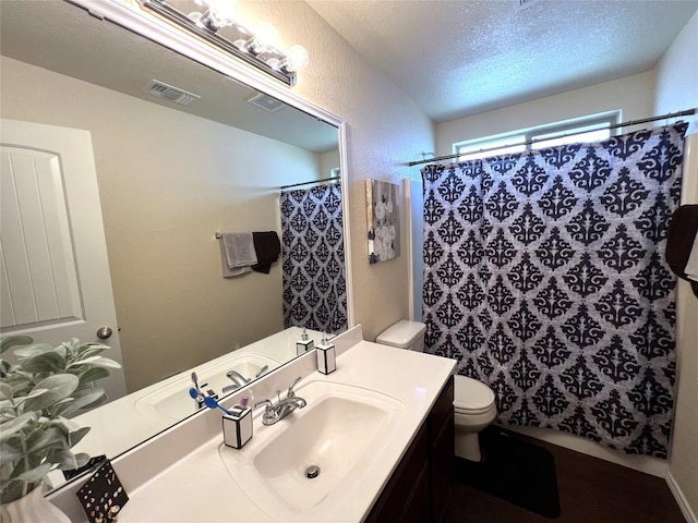 bathroom with walk in shower, vanity, toilet, and a textured ceiling