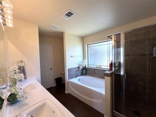 bathroom with vanity, hardwood / wood-style flooring, plus walk in shower, and a textured ceiling