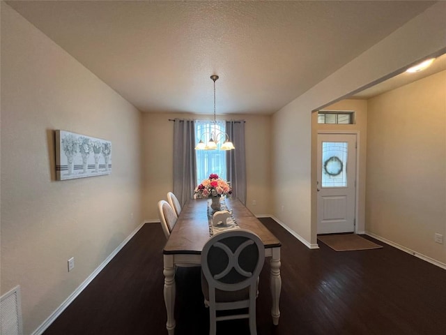 dining room featuring visible vents, dark wood finished floors, baseboards, and an inviting chandelier