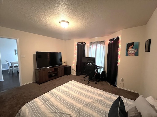 bedroom with a textured ceiling and dark colored carpet