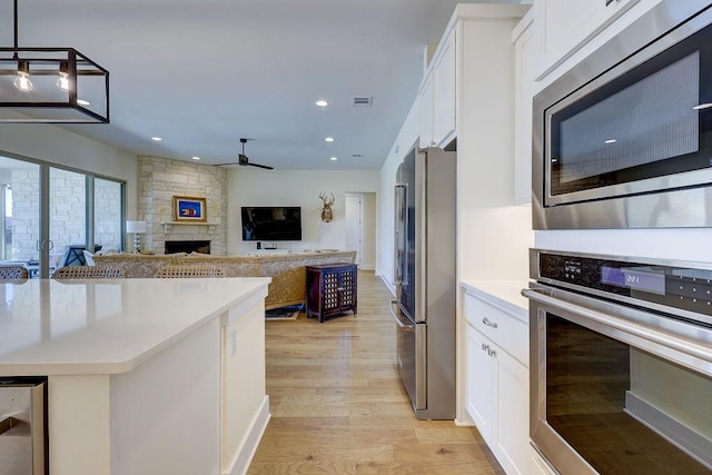 kitchen featuring white cabinetry, appliances with stainless steel finishes, light wood-type flooring, and wine cooler