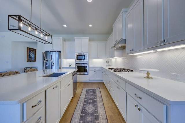 kitchen featuring white cabinetry, stainless steel appliances, sink, and a center island with sink