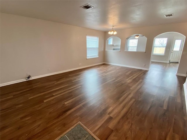 empty room featuring dark hardwood / wood-style floors and a notable chandelier