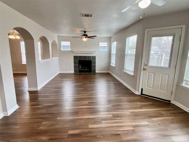 unfurnished living room with ceiling fan, a fireplace, and dark hardwood / wood-style flooring