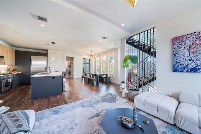 living area with visible vents, dark wood finished floors, a notable chandelier, and stairs