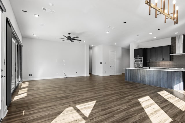 unfurnished living room with dark wood-type flooring and ceiling fan with notable chandelier