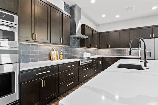 313 Starfire Dr, Dripping Springs, TX 78620 - kitchen featuring stainless steel appliances, wall chimney range hood, a sink, light stone countertops, and dark wood-type flooring