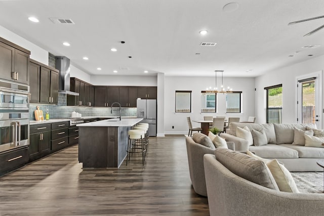 313 Starfire Dr, Dripping Springs, TX 78620 - kitchen with appliances with stainless steel finishes, open floor plan, wall chimney exhaust hood, a sink, and light countertops