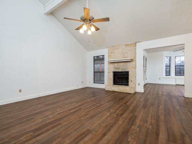 unfurnished living room featuring dark wood-type flooring, ceiling fan, high vaulted ceiling, a stone fireplace, and beamed ceiling