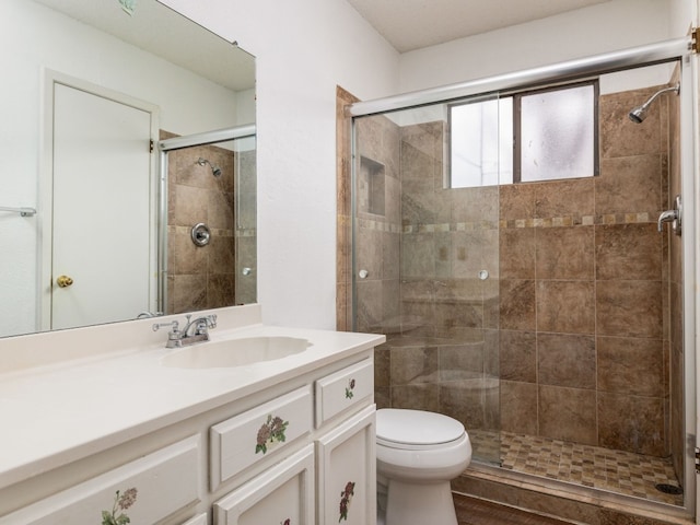 bathroom with walk in shower, vanity, and toilet