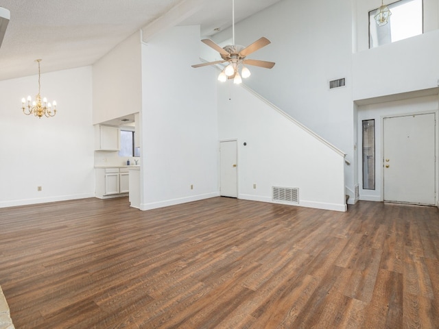 unfurnished living room with high vaulted ceiling, ceiling fan with notable chandelier, and dark hardwood / wood-style flooring