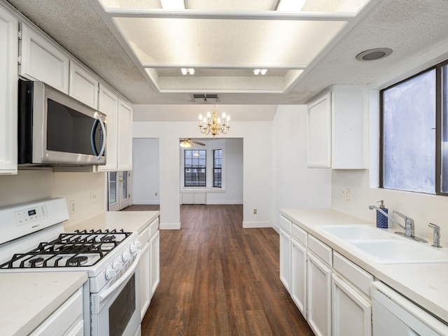 kitchen featuring sink, white appliances, hanging light fixtures, white cabinets, and a raised ceiling