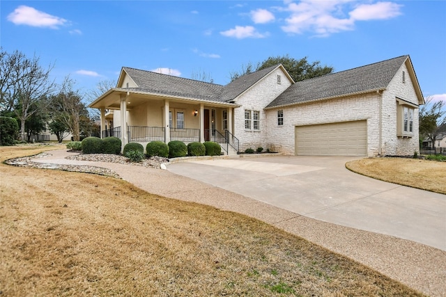 view of front of house featuring a garage, covered porch, and a front lawn