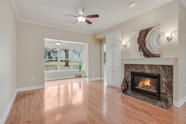 unfurnished living room with ornamental molding, ceiling fan, a high end fireplace, and light hardwood / wood-style flooring