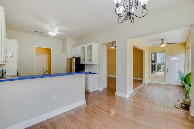 kitchen with backsplash, stainless steel fridge, white cabinets, and light wood-type flooring