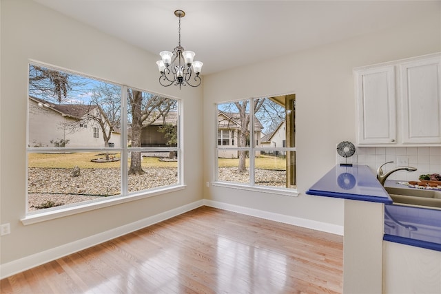 unfurnished dining area with sink, a chandelier, and light wood-type flooring