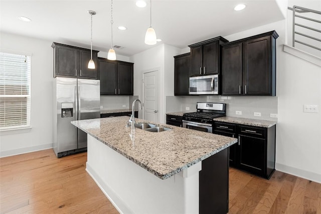 2211 Capulet St, Austin, TX 78741 - kitchen with stainless steel appliances, a sink, light wood-type flooring, a center island with sink, and tasteful backsplash