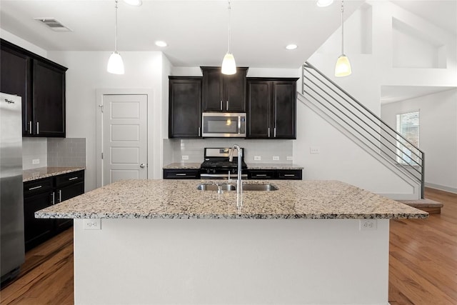 2211 Capulet St, Austin, TX 78741 - kitchen with stainless steel appliances, a sink, wood finished floors, backsplash, and recessed lighting
