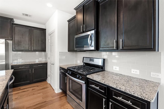 2211 Capulet St, Austin, TX 78741 - kitchen with stainless steel appliances, light wood-style flooring, light stone counters, tasteful backsplash, and recessed lighting