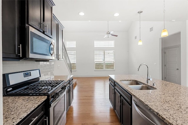 2211 Capulet St, Austin, TX 78741 - kitchen with appliances with stainless steel finishes, a sink, light wood-style flooring, ceiling fan, and decorative backsplash