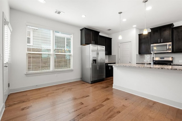 2211 Capulet St, Austin, TX 78741 - kitchen with appliances with stainless steel finishes, light wood-type flooring, light stone countertops, tasteful backsplash, and recessed lighting
