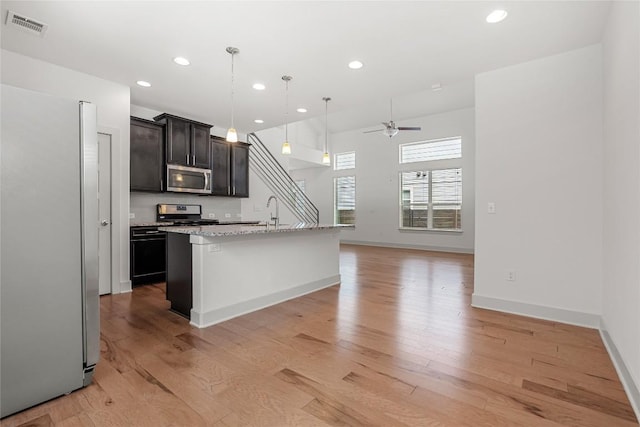 2211 Capulet St, Austin, TX 78741 - kitchen featuring appliances with stainless steel finishes, ceiling fan, recessed lighting, light wood finished floors, and open floor plan