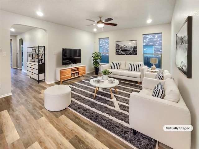 living area with arched walkways, recessed lighting, wood finished floors, a ceiling fan, and baseboards