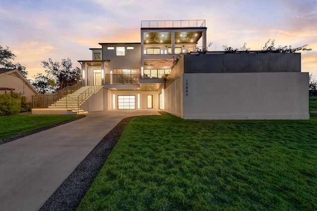 12885 Park Dr, Austin, TX 78732 - view of front of home with a balcony, concrete driveway, stairs, a yard, and an attached garage