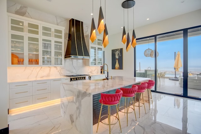 12885 Park Dr, Austin, TX 78732 - kitchen featuring custom exhaust hood, light marble finish floors, light stone counters, tasteful backsplash, and a sink