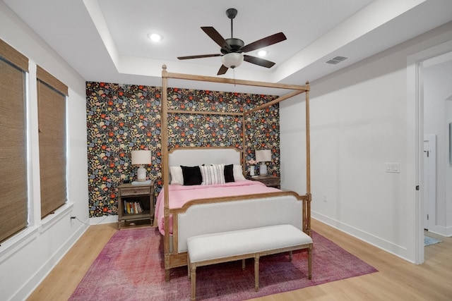 bedroom featuring ceiling fan, a raised ceiling, and hardwood / wood-style floors