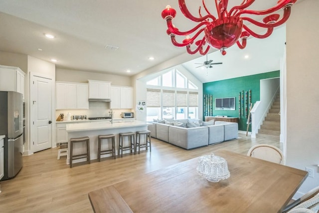 dining area featuring ceiling fan, lofted ceiling, sink, and light hardwood / wood-style floors